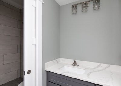 Modern bathroom interior with gray vanity and wall-mounted light fixture.