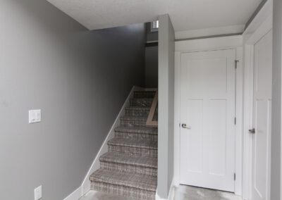 Interior of a modern home showing a staircase with grey walls and a white door.