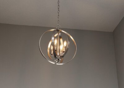 A modern spherical chandelier with exposed bulbs hangs from a gray ceiling.