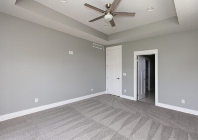 Empty room with gray walls, carpeted floor, and a ceiling fan.