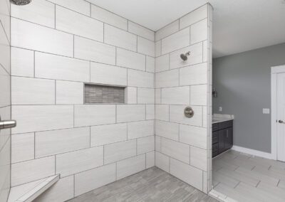 Modern bathroom with a tiled walk-in shower and a vanity cabinet in the background.