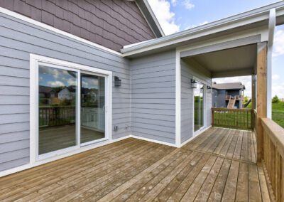 Wooden deck of a suburban home with sliding glass doors and an open porch area.