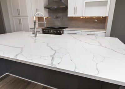 Modern kitchen with white marble countertop and stainless steel appliances.