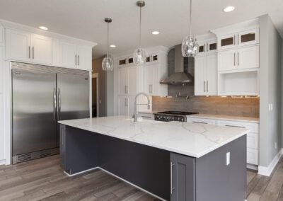 Modern kitchen with white cabinetry, stainless steel appliances, and a central island with a marble countertop.