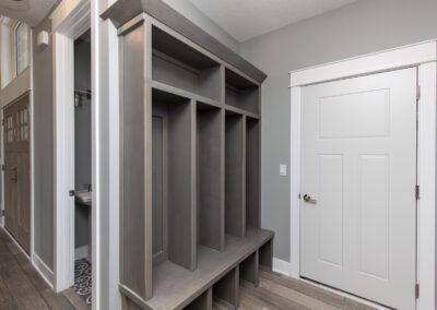 Modern home interior featuring a built-in hallway storage unit with shelving and a bench, adjacent to a closed white door.