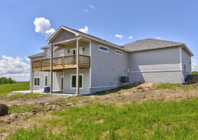 Newly constructed two-story home with a balcony and unfinished lawn.