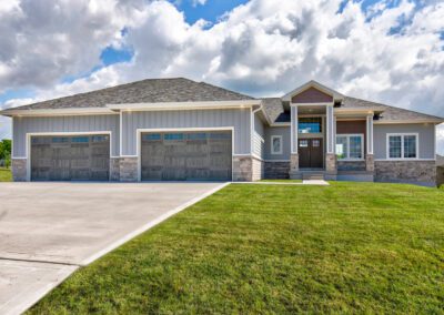 Modern single-story house with a three-car garage and a landscaped front lawn.